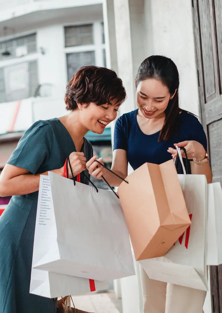 happy asian women showing purchases to each other