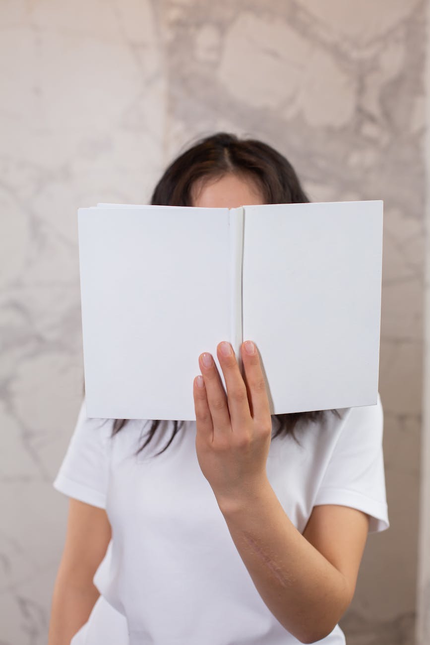 anonymous woman covering face with mock up notepad